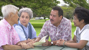 four senior adults chatting around an outdoor table