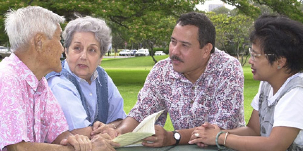 four senior adults chatting around an outdoor table
