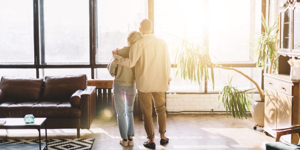 elder couple embracing while looking out the window