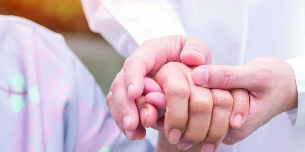 Doctor holding a patient's hand in a caring and compassionate way