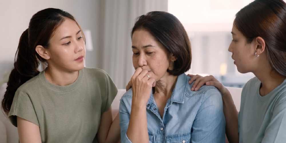 a mother is consoled by her two daughters after a breast cancer diagnosis