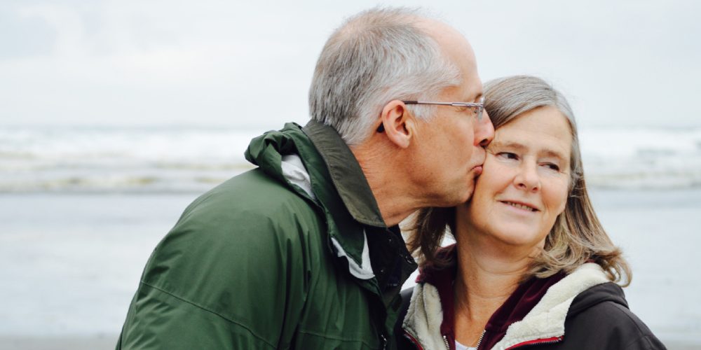 a husband kissing his wife on a beach